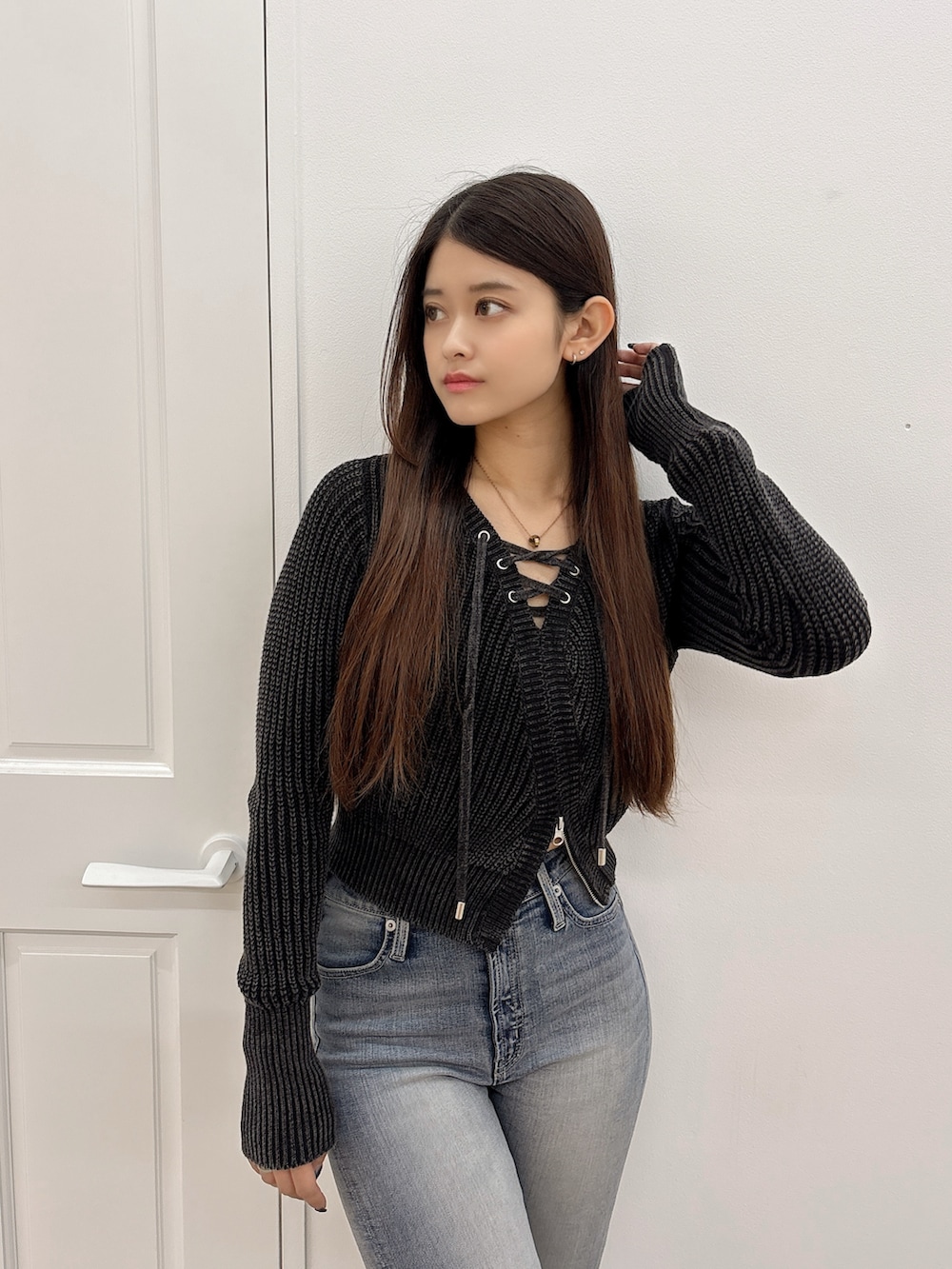 ブラック系のブーツ、ブラック系のニット/セーター、ブルー系のデニムパンツを着用したレディースの秋コーディネートの4枚目の写真