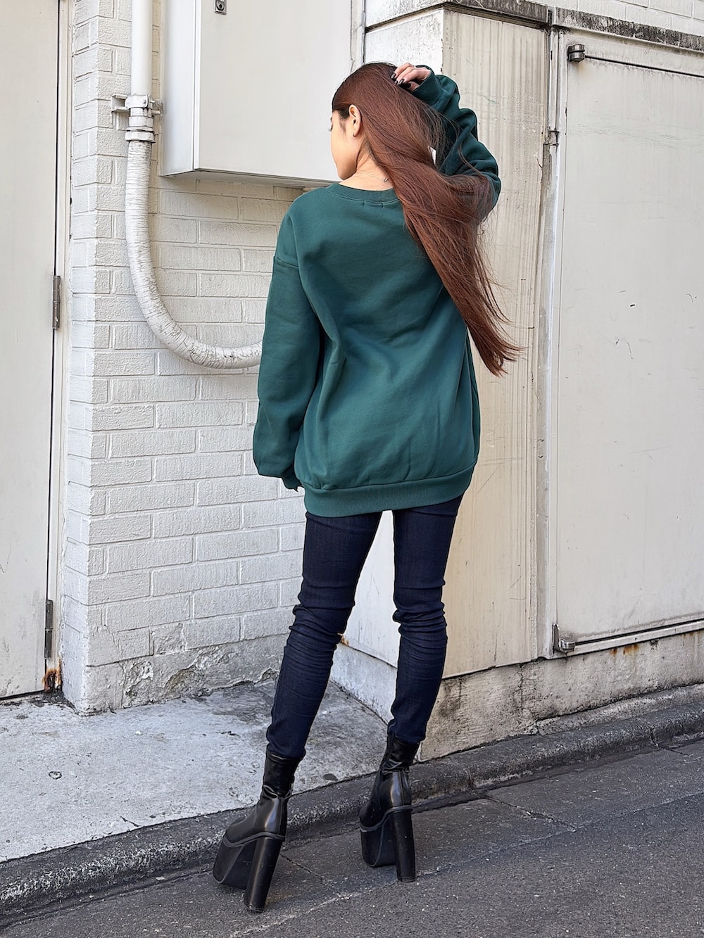 グリーン系のスウェット、ブルー系のデニムパンツ、ブラック系のブーツを着用したレディースの冬コーディネートの3枚目の写真