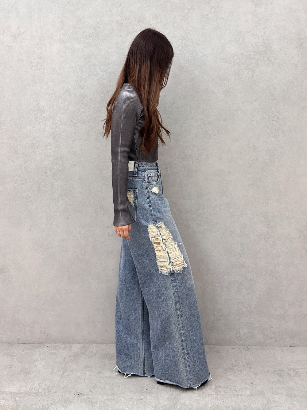 ブラック系のニット/セーター、ブルー系のデニムパンツ、ブラック系のサンダルを着用したレディースの夏コーディネートの2枚目の写真