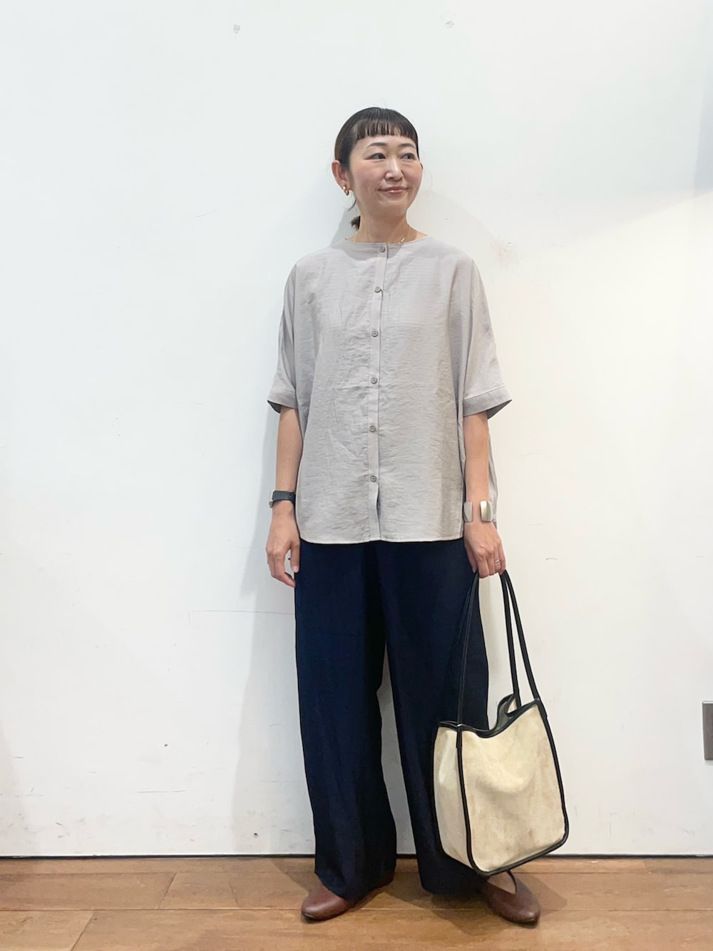 グレー系のシャツ/ブラウス、ブラウン系のパンプス、ベージュ系のトートバッグを着用したレディースの夏コーディネートの2枚目の写真