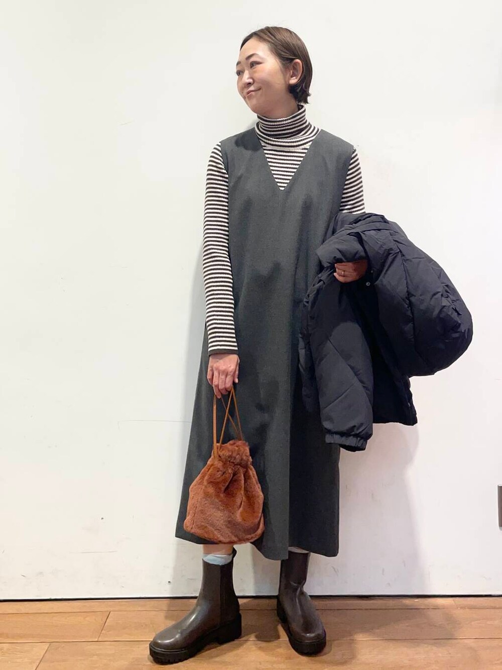 ブラック系のダウンジャケット/コート、グレー系のワンピース、ブラウン系のブーツを着用したレディースの冬コーディネートの6枚目の写真