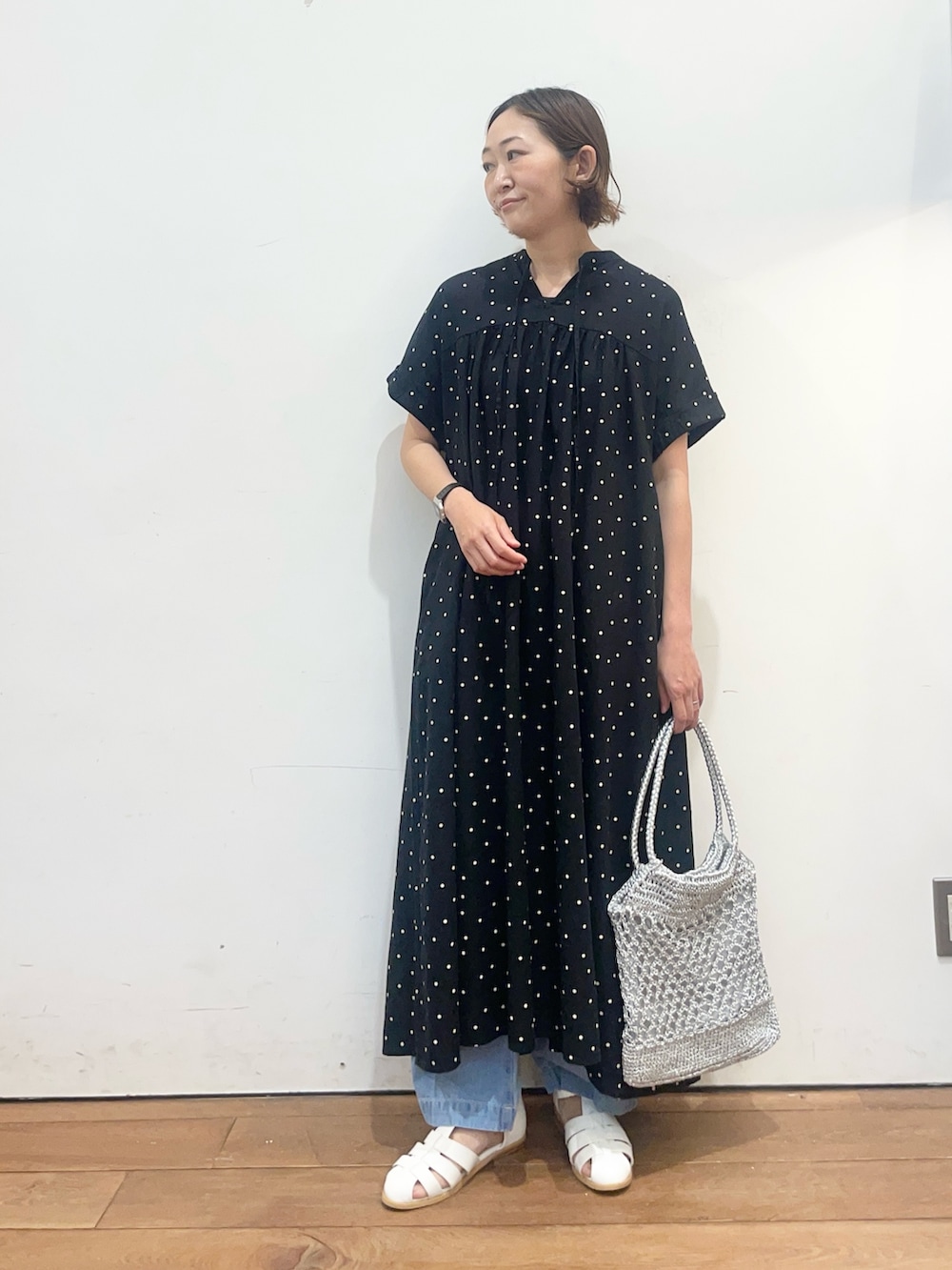 ブラック系のワンピース、ホワイト系のサンダル、シルバー系のトートバッグを着用したレディースの春コーディネートの2枚目の写真