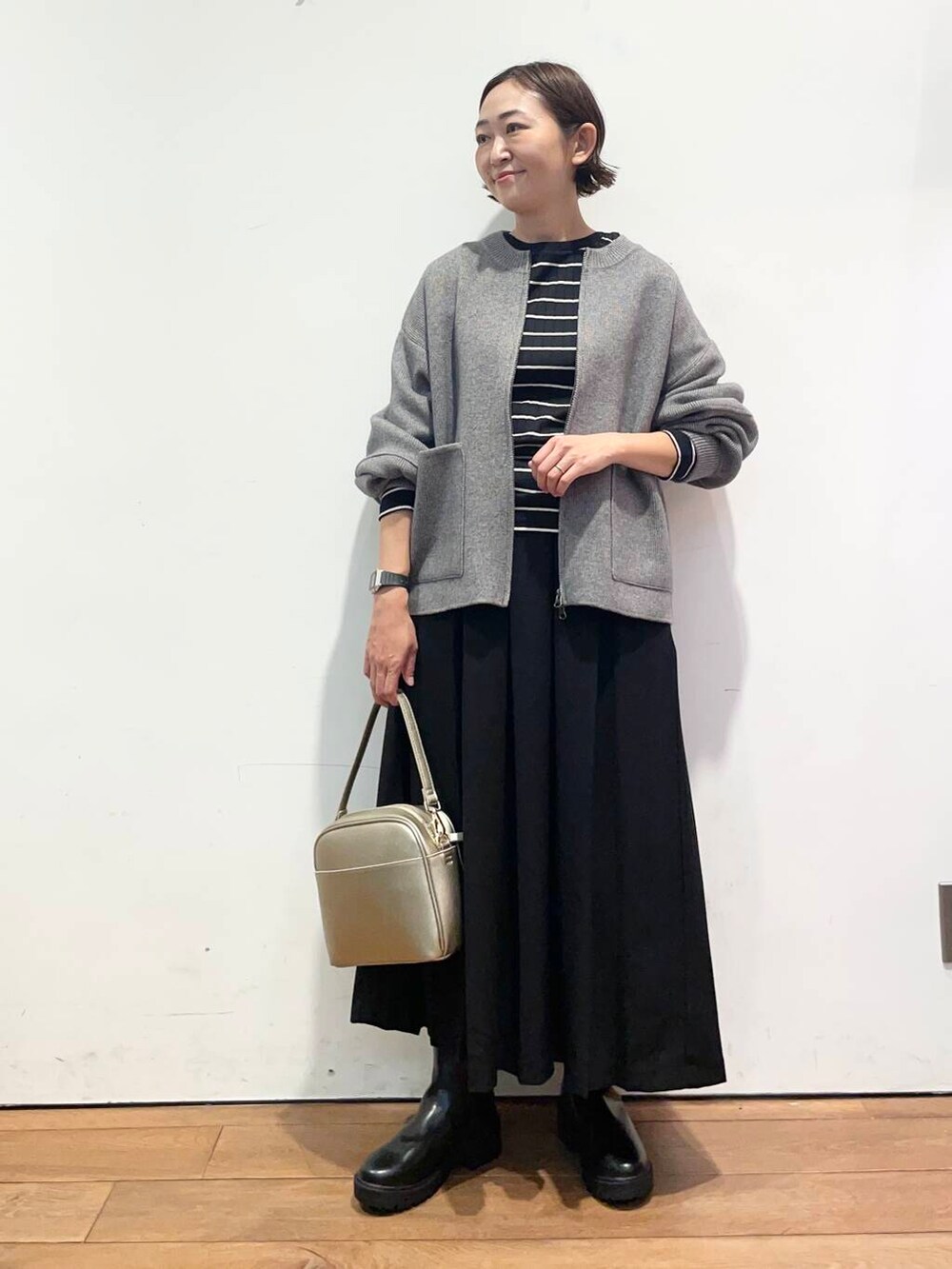 ブラック系のTシャツ/カットソー、ゴールド系のショルダーバッグ、ブラック系のブーツを着用したレディースの秋コーディネートの3枚目の写真