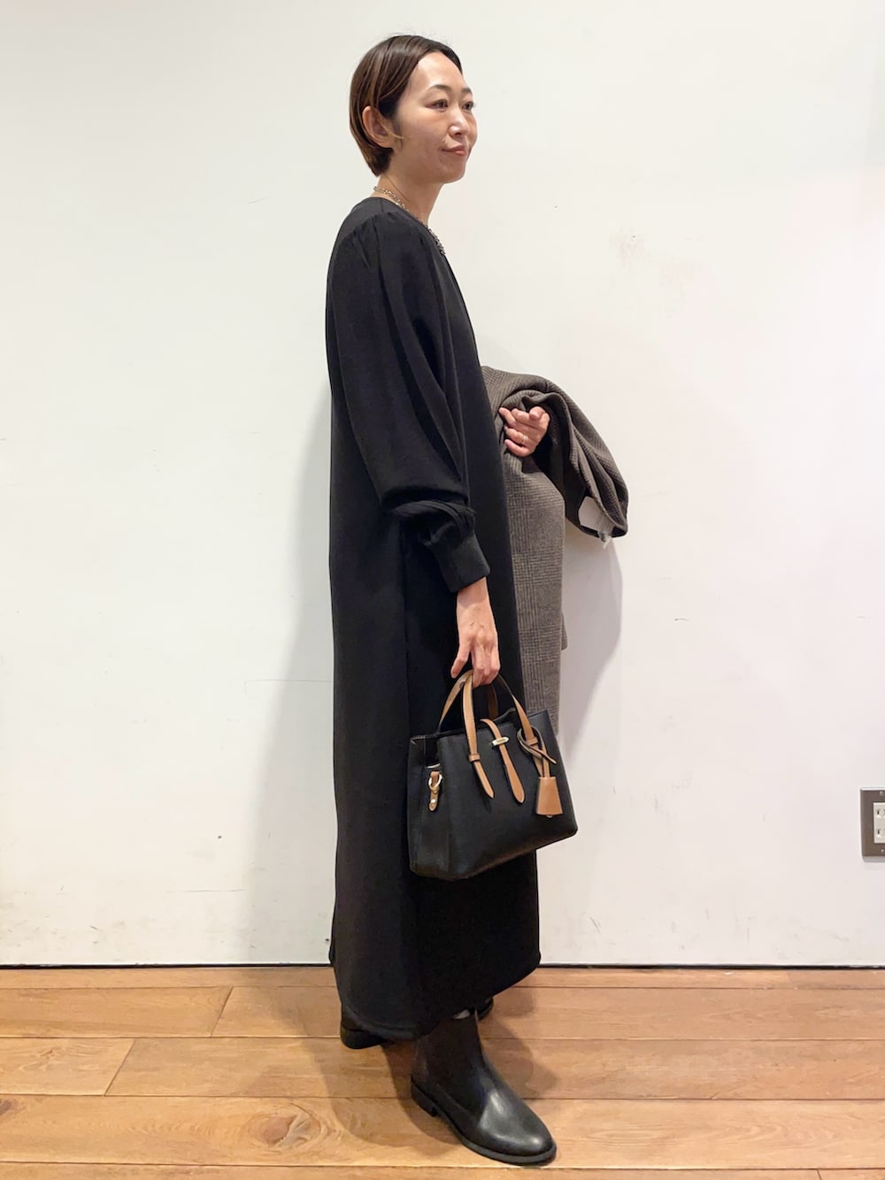 ブラック系のブーツ、ブラック系のハンドバッグ、その他のその他アウターを着用したレディースの秋コーディネートの7枚目の写真