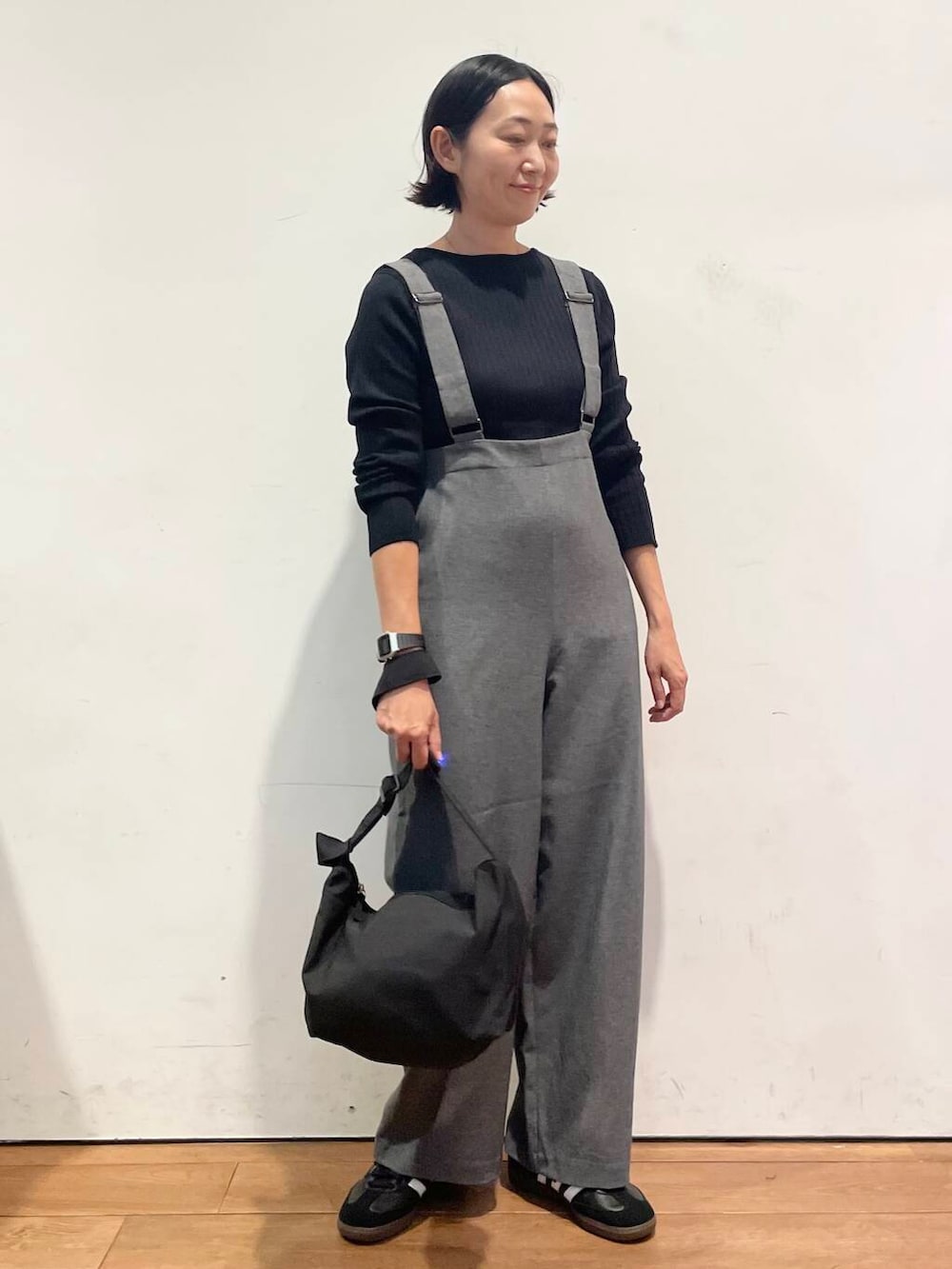 ブラック系のショルダーバッグ、グレー系のサロペット/オーバーオール、ブラック系のスニーカーを着用したレディースの秋コーディネートの2枚目の写真