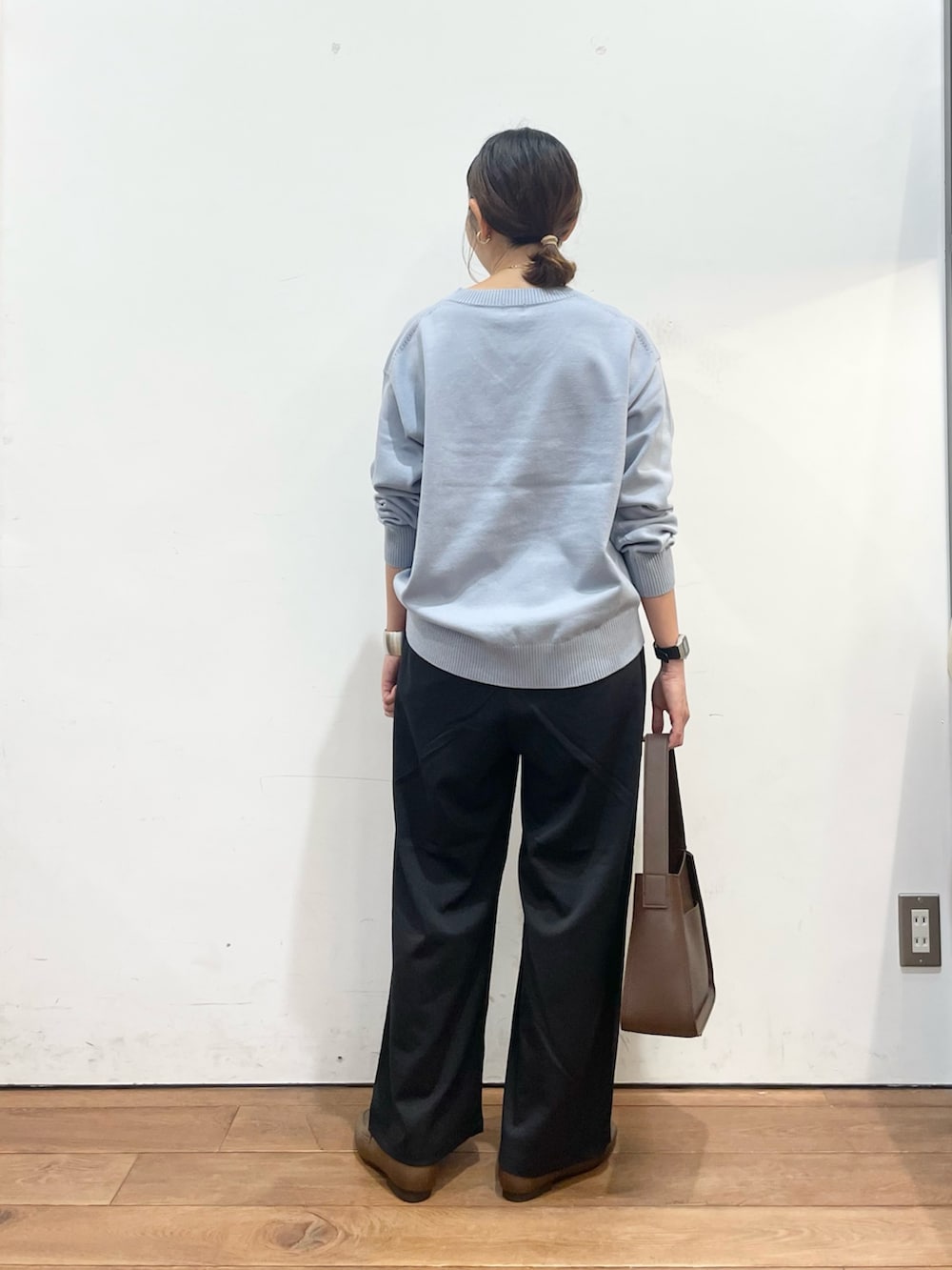 ブルー系のニット/セーター、ブラウン系のローファー、ブラウン系のハンドバッグを着用したレディースの秋コーディネートの5枚目の写真
