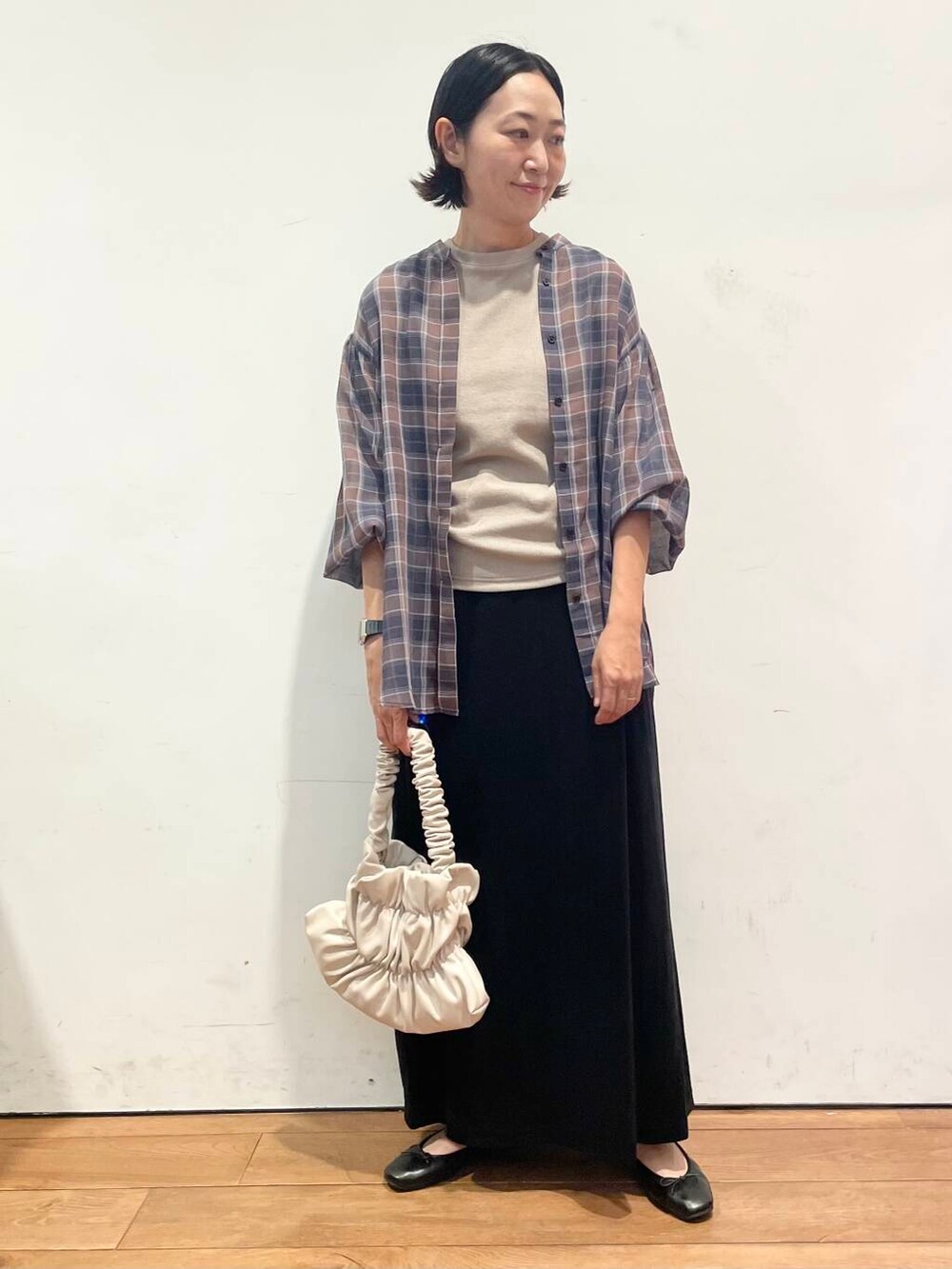 ホワイト系のハンドバッグ、ブラック系のワンピース、ブラック系のスカートを着用したレディースの秋コーディネートの4枚目の写真