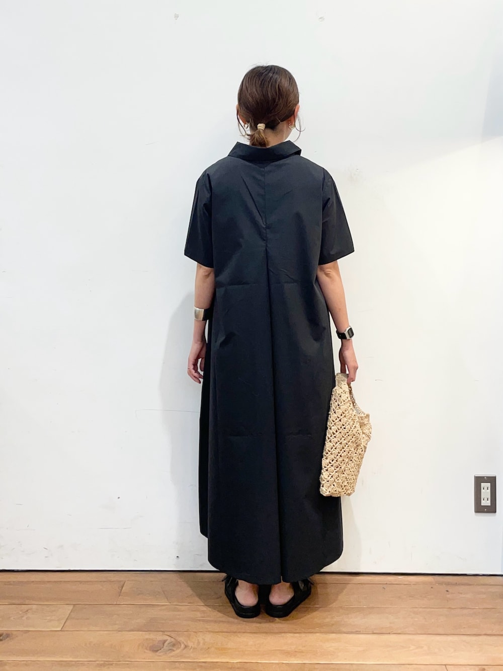グレー系のワンピース、ベージュ系のハンドバッグ、ブラック系のサンダルを着用したレディースの夏コーディネートの4枚目の写真