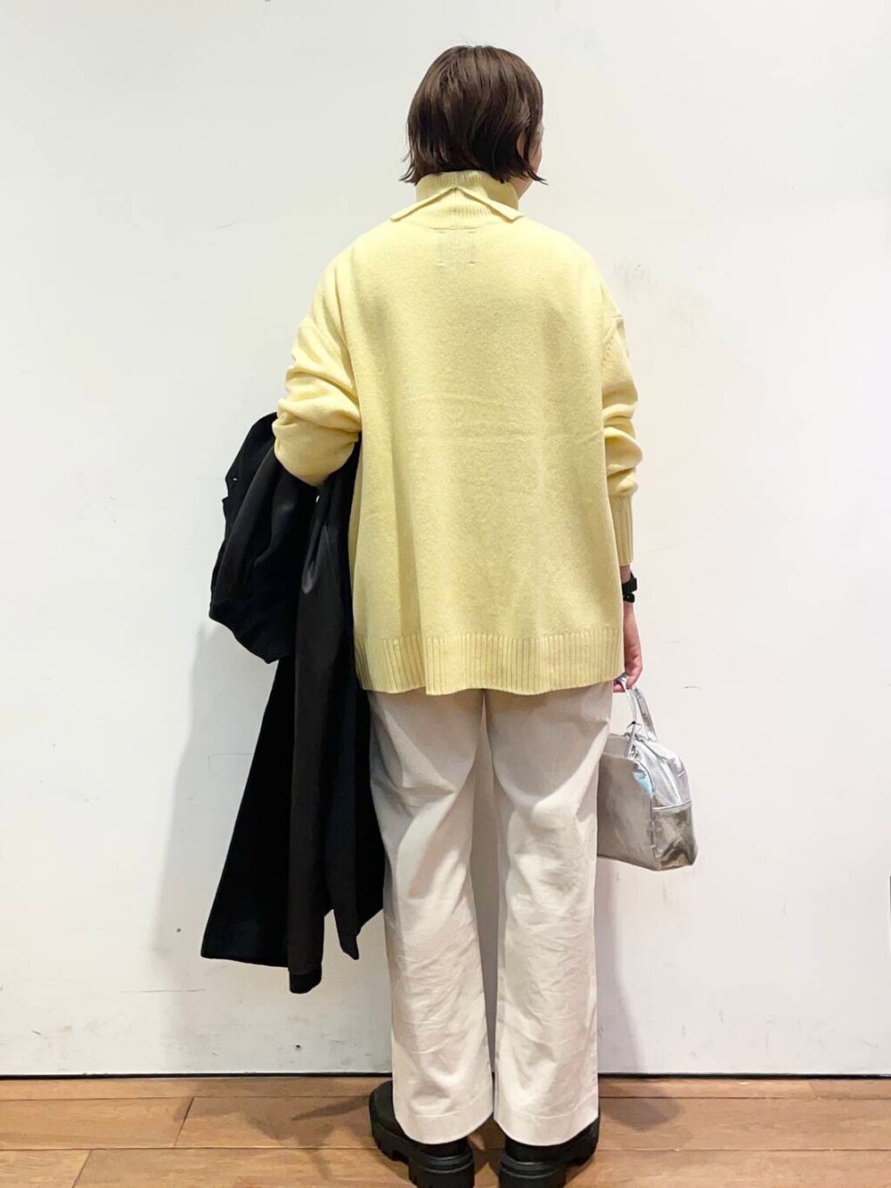 ブラック系のその他アウター、イエロー系のニット/セーター、ブラック系のブーツを着用したレディースの冬コーディネートの8枚目の写真