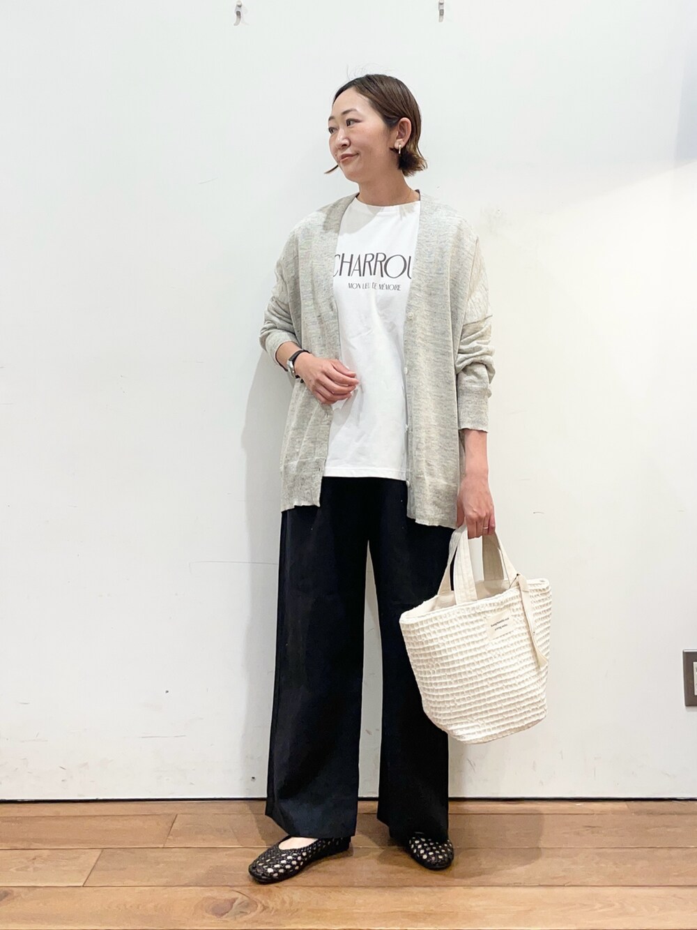ホワイト系のTシャツ/カットソー、グレー系のカーディガン/ボレロ、ブラック系のサンダルを着用したレディースの春コーディネートの2枚目の写真
