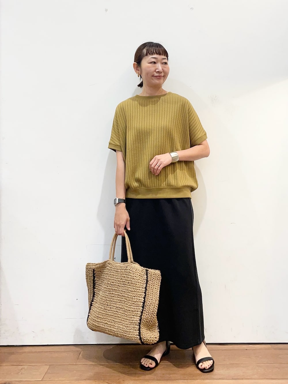 イエロー系のTシャツ/カットソー、ベージュ系のトートバッグ、ブラック系のスカートを着用したレディースの夏コーディネートの3枚目の写真