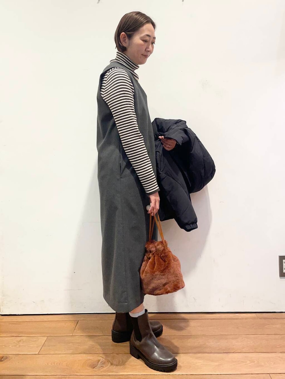 ブラック系のダウンジャケット/コート、グレー系のワンピース、ブラウン系のブーツを着用したレディースの冬コーディネートの7枚目の写真