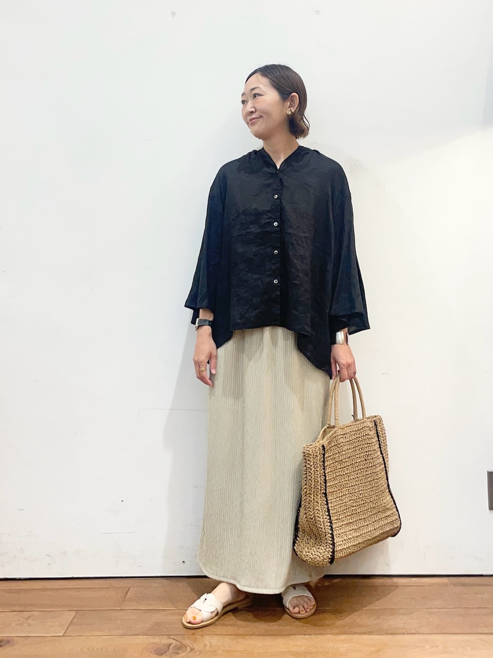 ブラック系のシャツ/ブラウス、ベージュ系のスカート、ベージュ系のトートバッグを着用したレディースの春コーディネートの2枚目の写真