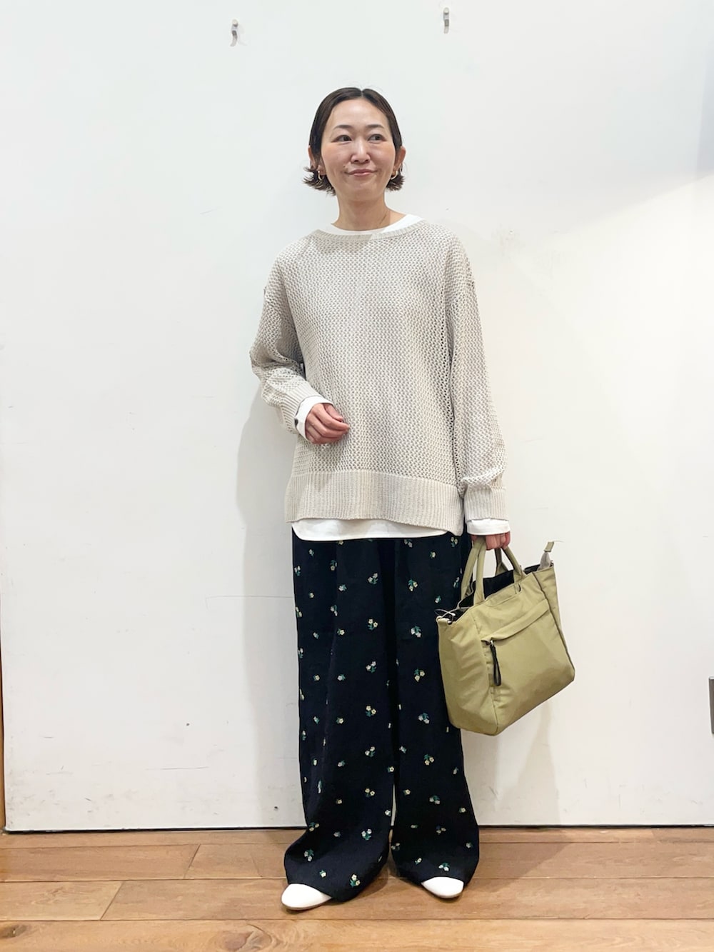 グレー系のニット/セーター、ホワイト系のTシャツ/カットソー、ベージュ系のトートバッグを着用したレディースの春コーディネートの2枚目の写真