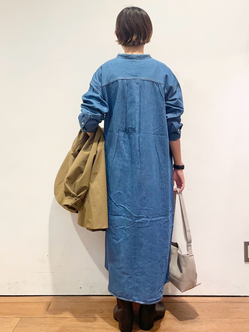 ベージュ系のその他アウター、ブルー系のワンピース、ブラック系のブーツを着用したレディースの秋コーディネートの7枚目の写真