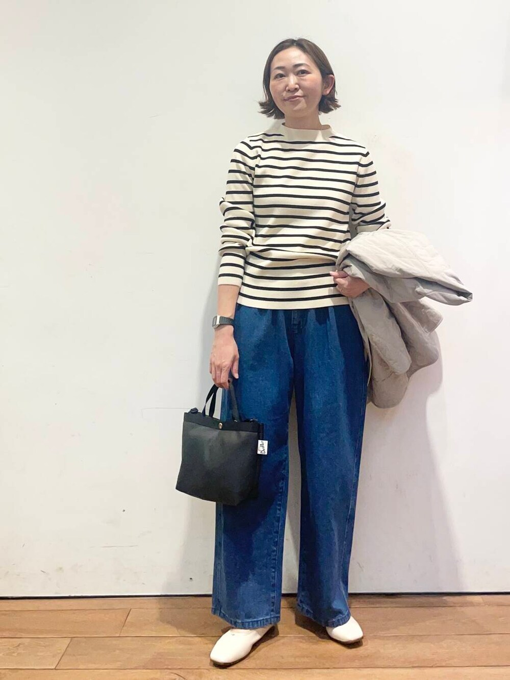 ブルー系のデニムパンツ、グレー系のダウンジャケット/コート、ブラック系のニット/セーターを着用したレディースの春コーディネートの7枚目の写真