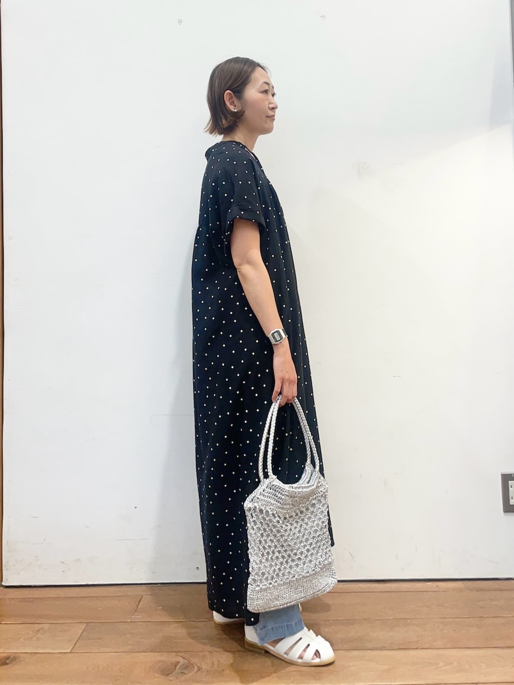 ブラック系のワンピース、ホワイト系のサンダル、シルバー系のトートバッグを着用したレディースの春コーディネートの3枚目の写真
