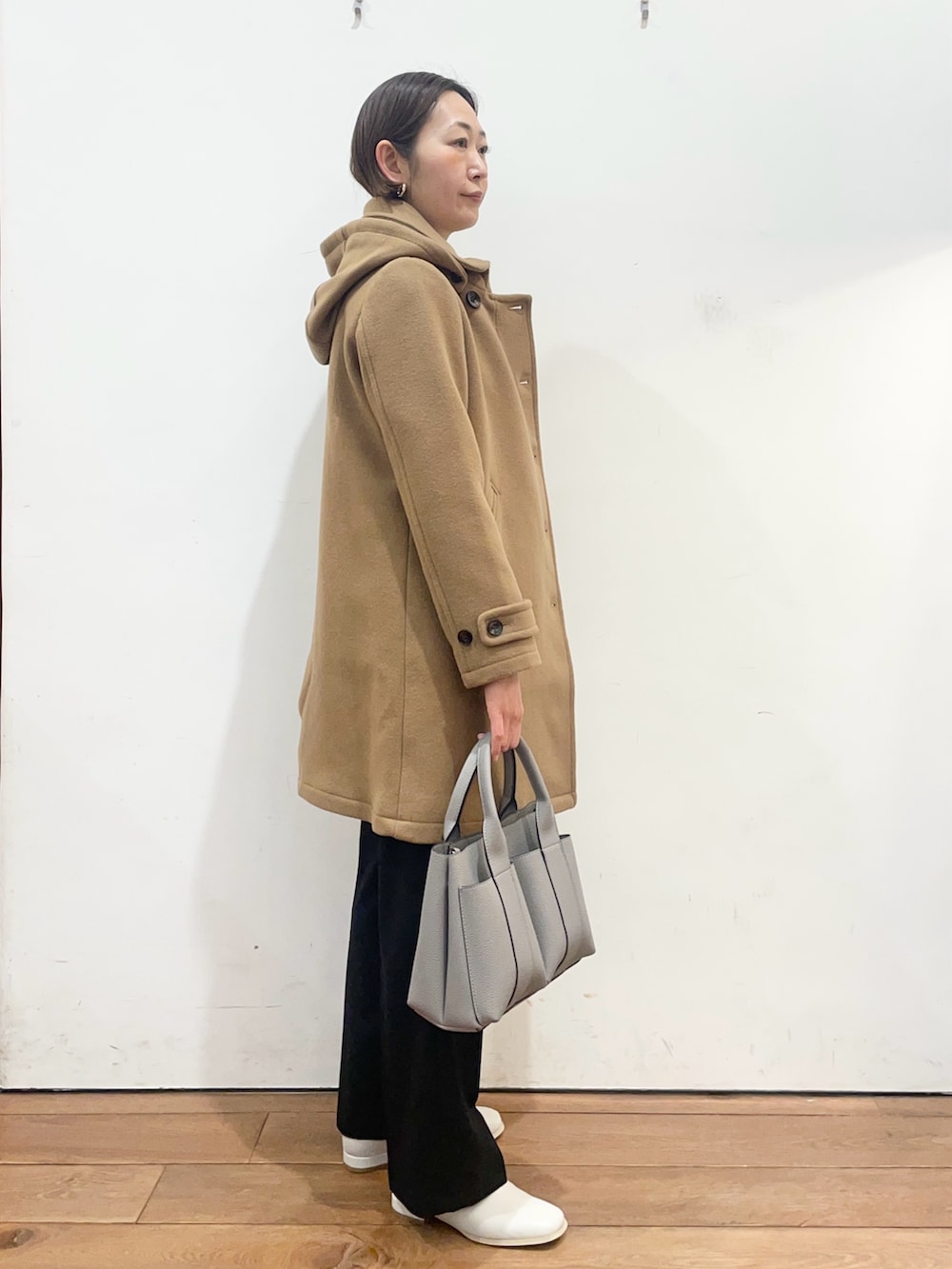 グレー系のトートバッグ、ホワイト系のブーツ、イエロー系のその他アウターを着用したレディースの冬コーディネートの3枚目の写真