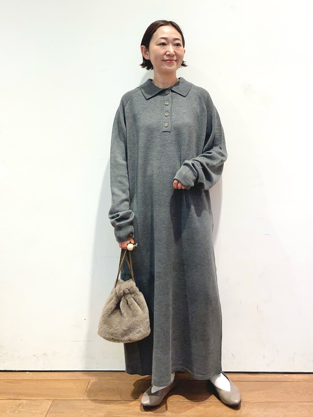 グレー系のワンピース、ブラウン系のショルダーバッグ、ベージュ系のパンプスを着用したレディースの秋コーディネートの2枚目の写真