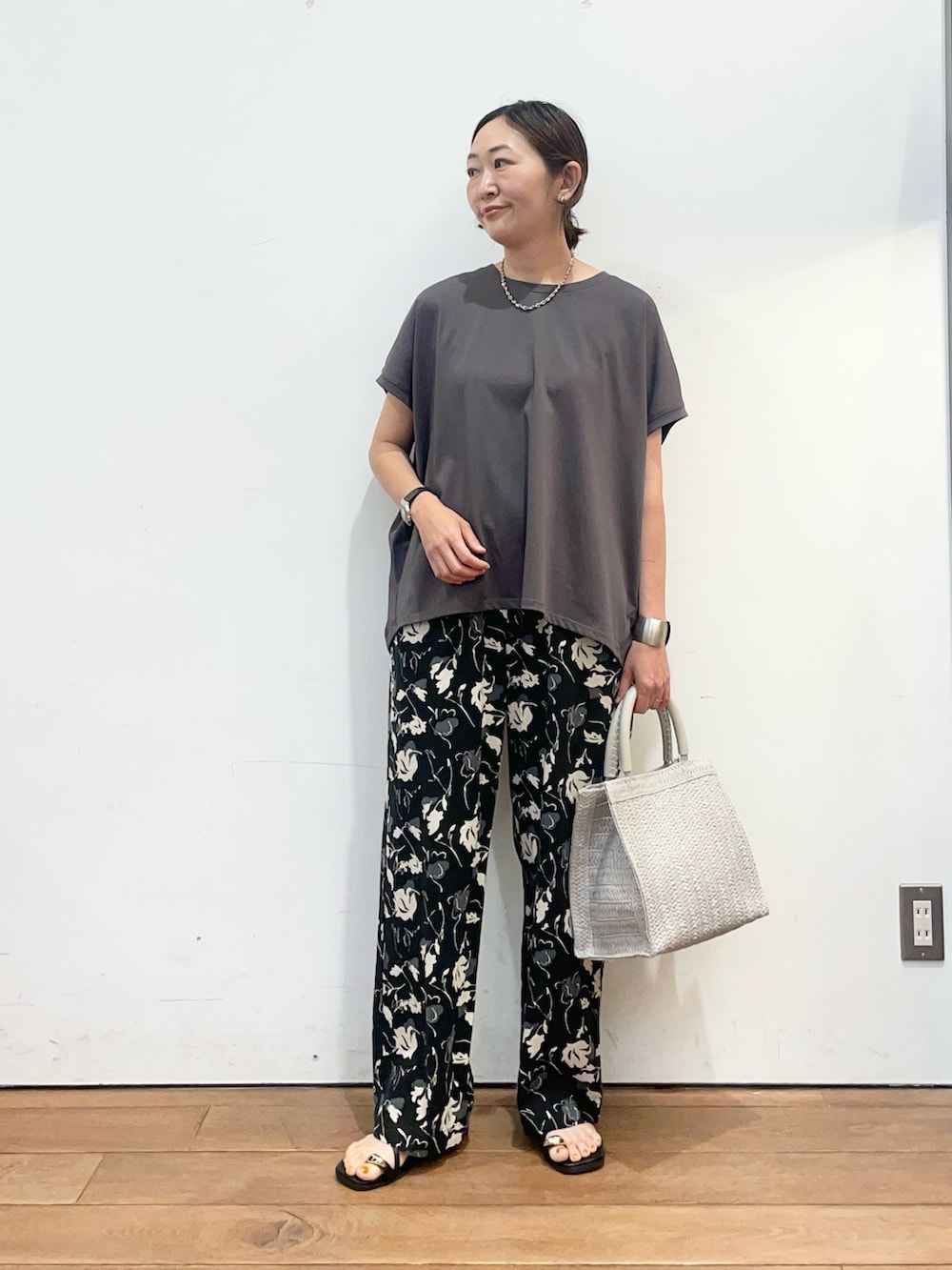 グレー系のTシャツ/カットソー、グレー系のハンドバッグ、ブラック系のサンダルを着用したレディースの夏コーディネートの3枚目の写真