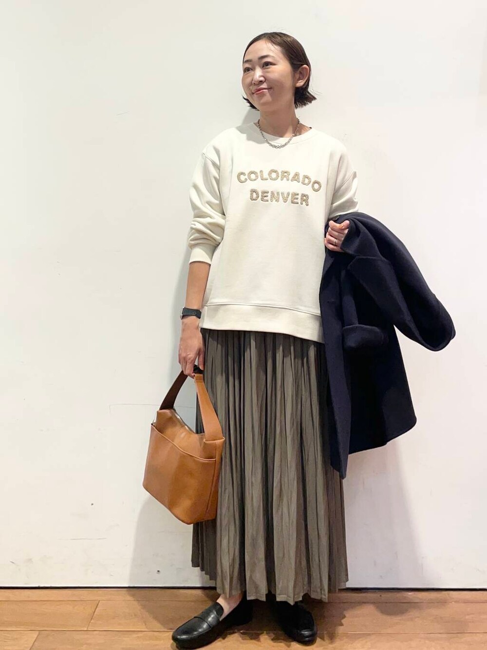 ブルー系のその他アウター、イエロー系のショルダーバッグ、ベージュ系のスカートを着用したレディースの秋コーディネートの5枚目の写真