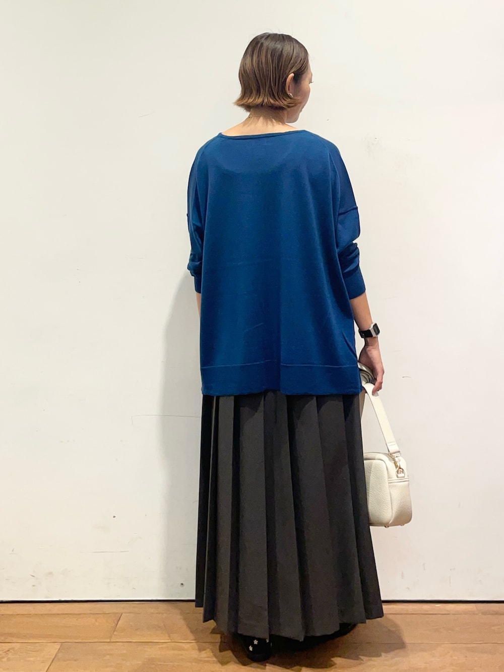 ブルー系のニット/セーター、ブラック系のスニーカー、グレー系のスカートを着用したレディースの秋コーディネートの5枚目の写真