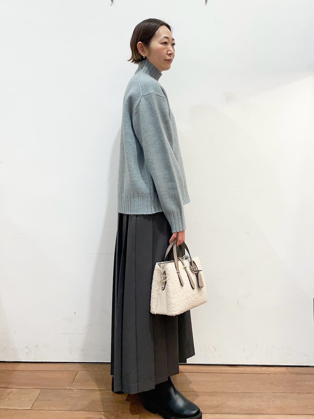 グリーン系のニット/セーター、グレー系のスカート、ブラック系のブーツを着用したレディースの冬コーディネートの3枚目の写真