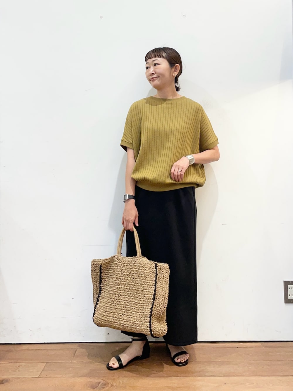 イエロー系のTシャツ/カットソー、ベージュ系のトートバッグ、ブラック系のスカートを着用したレディースの夏コーディネートの2枚目の写真