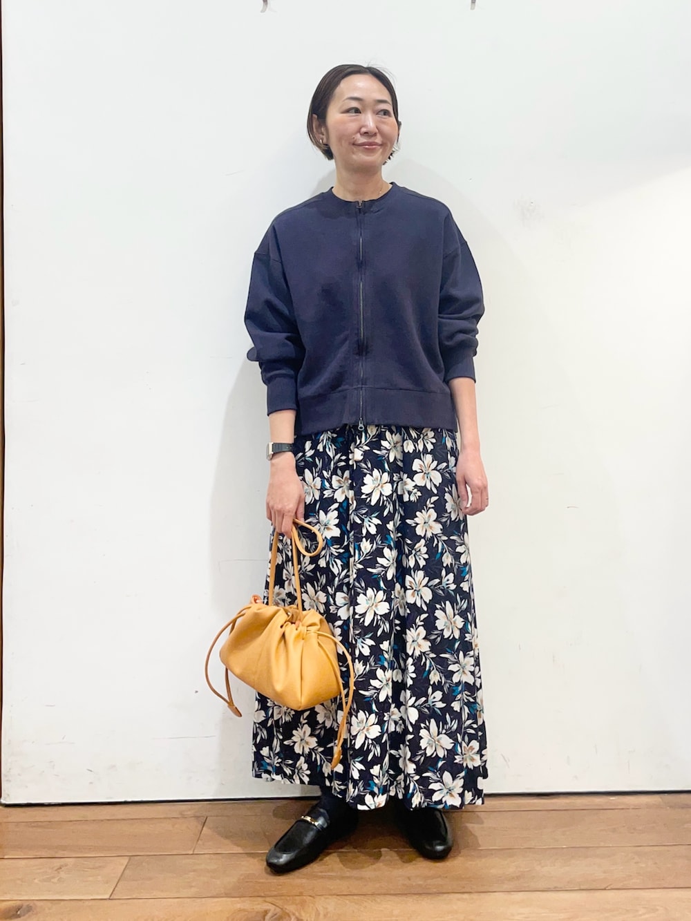 ブルー系のカーディガン/ボレロ、ブルー系のスカート、オレンジ系のショルダーバッグを着用したレディースの春コーディネートの2枚目の写真