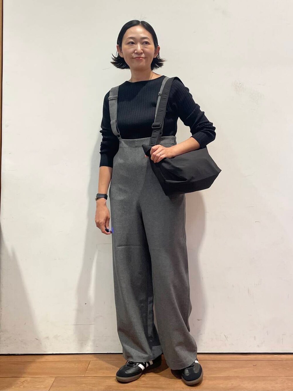 ブラック系のショルダーバッグ、グレー系のサロペット/オーバーオール、ブラック系のスニーカーを着用したレディースの秋コーディネートの3枚目の写真