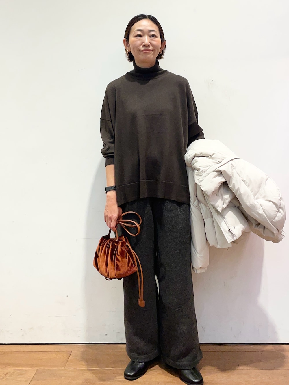 ホワイト系のダウンジャケット/コート、ブラウン系のニット/セーター、ブラック系のブーツを着用したレディースの秋コーディネートの6枚目の写真