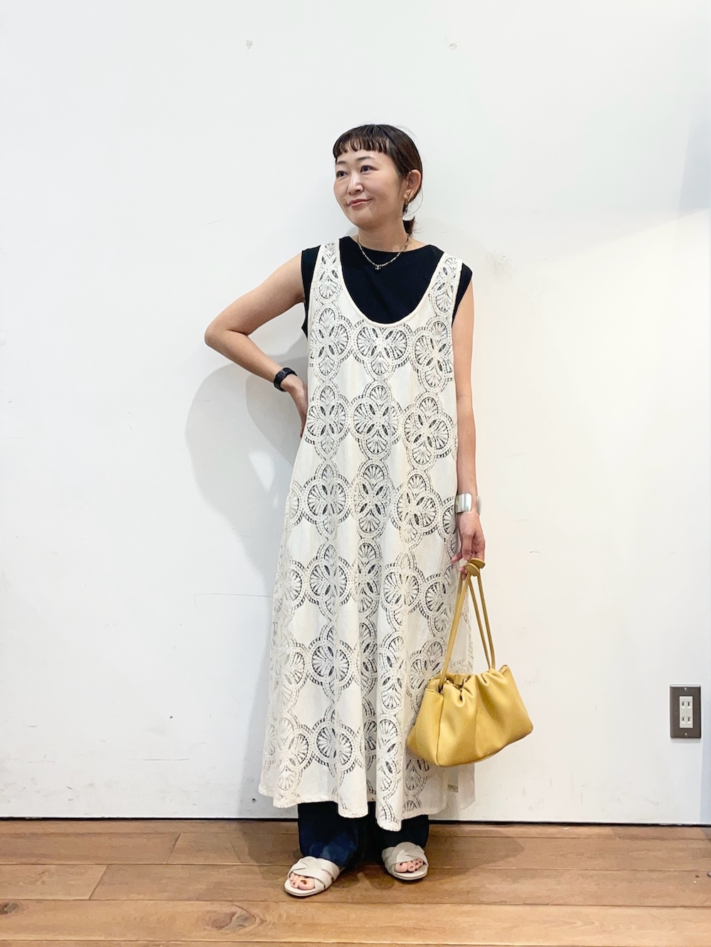 ベージュ系のワンピース、ブラック系のタンクトップ、ベージュ系のサンダルを着用したレディースの夏コーディネートの2枚目の写真