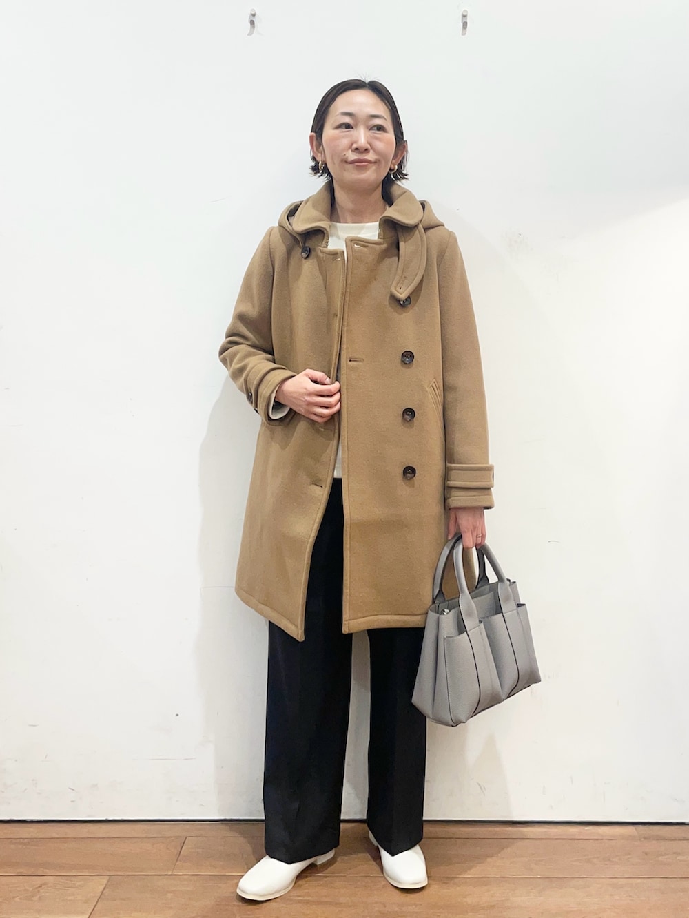 グレー系のトートバッグ、ホワイト系のブーツ、イエロー系のその他アウターを着用したレディースの冬コーディネートの2枚目の写真