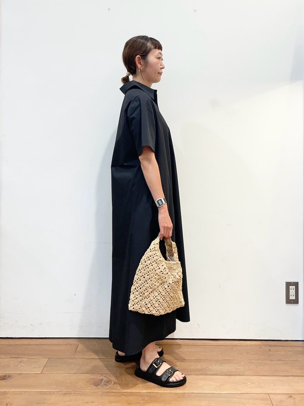 グレー系のワンピース、ベージュ系のハンドバッグ、ブラック系のサンダルを着用したレディースの夏コーディネートの3枚目の写真