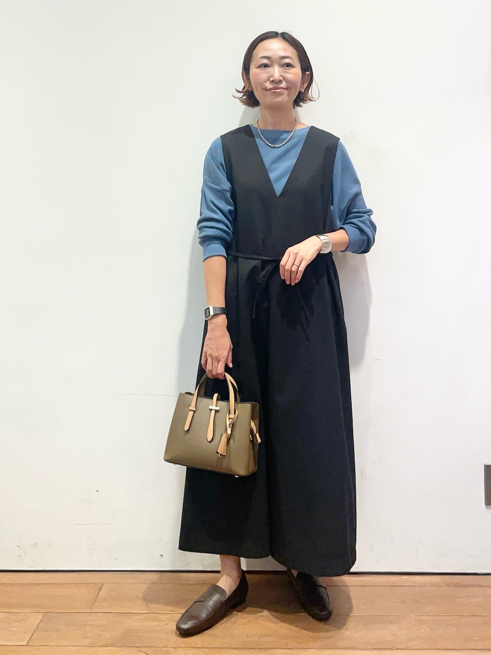 ブラック系のワンピース、ブルー系のTシャツ/カットソー、ブラウン系のパンプスを着用したレディースの秋コーディネートの4枚目の写真