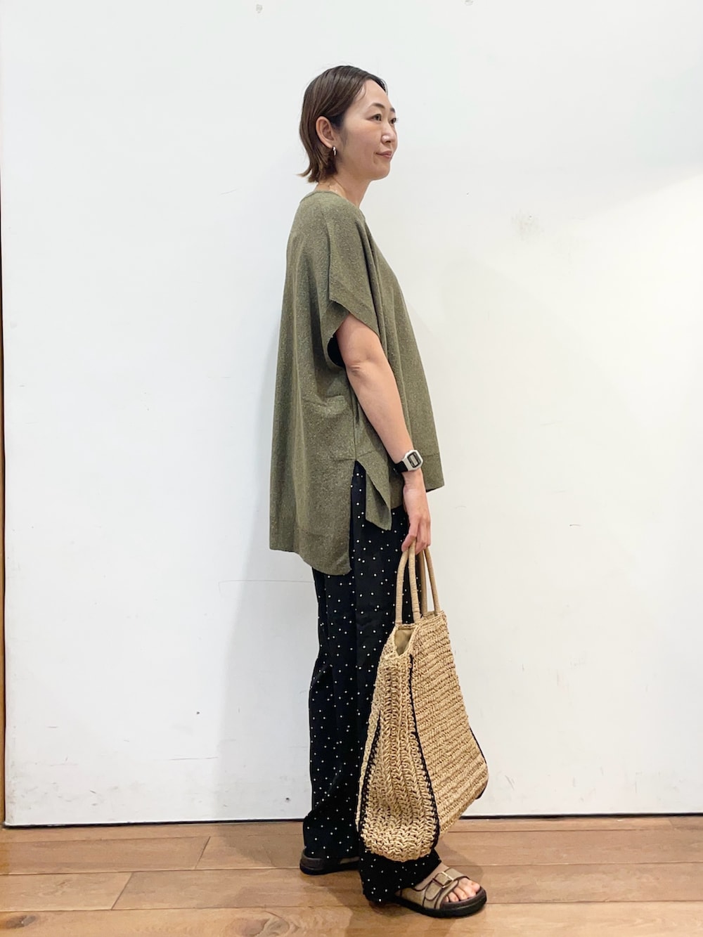 グリーン系のニット/セーター、ブラック系のその他パンツ、ベージュ系のトートバッグを着用したレディースの春コーディネートの3枚目の写真
