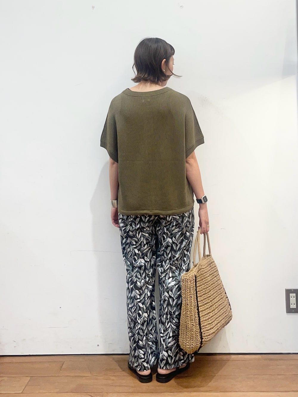 グリーン系のニット/セーター、ブラック系のその他パンツ、ベージュ系のトートバッグを着用したレディースの夏コーディネートの4枚目の写真