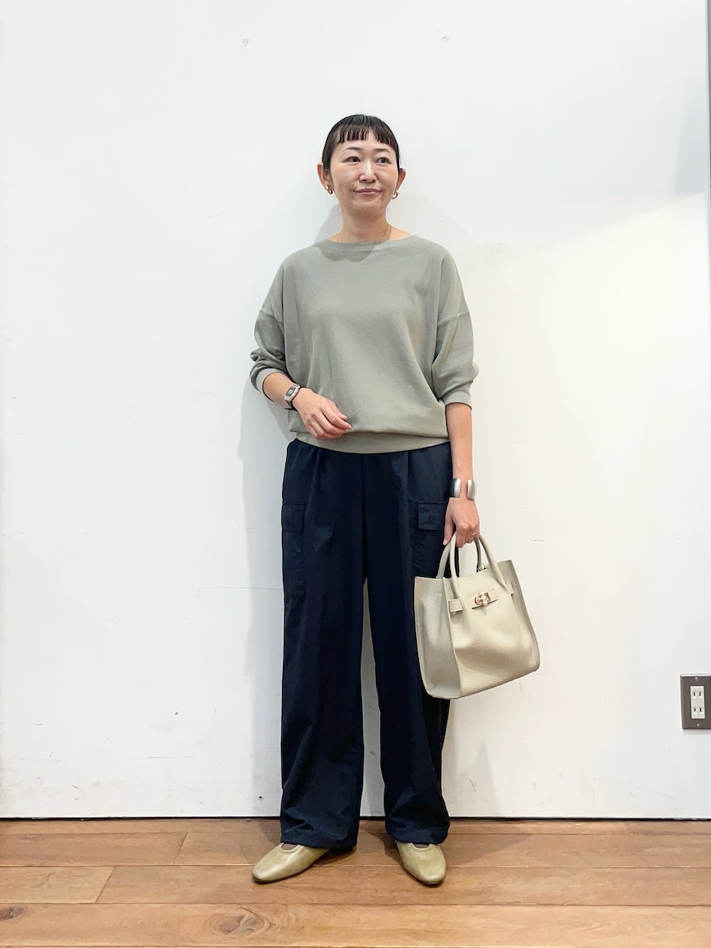 グリーン系のTシャツ/カットソー、グレー系のハンドバッグ、ブラウン系のスリッポンを着用したレディースの秋コーディネートの2枚目の写真