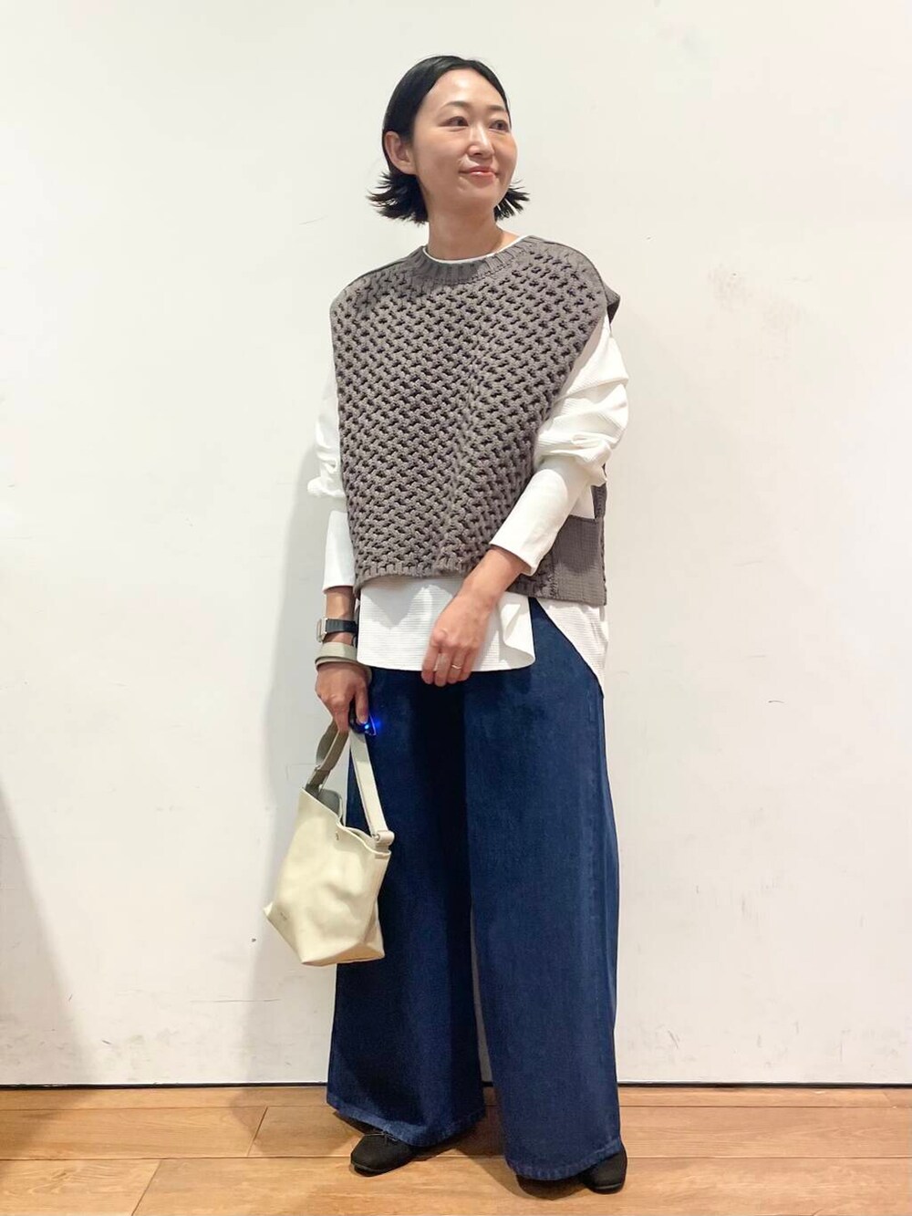 ブラック系のバレエシューズ、ブルー系のデニムパンツ、グレー系のベストを着用したレディースの秋コーディネートの4枚目の写真