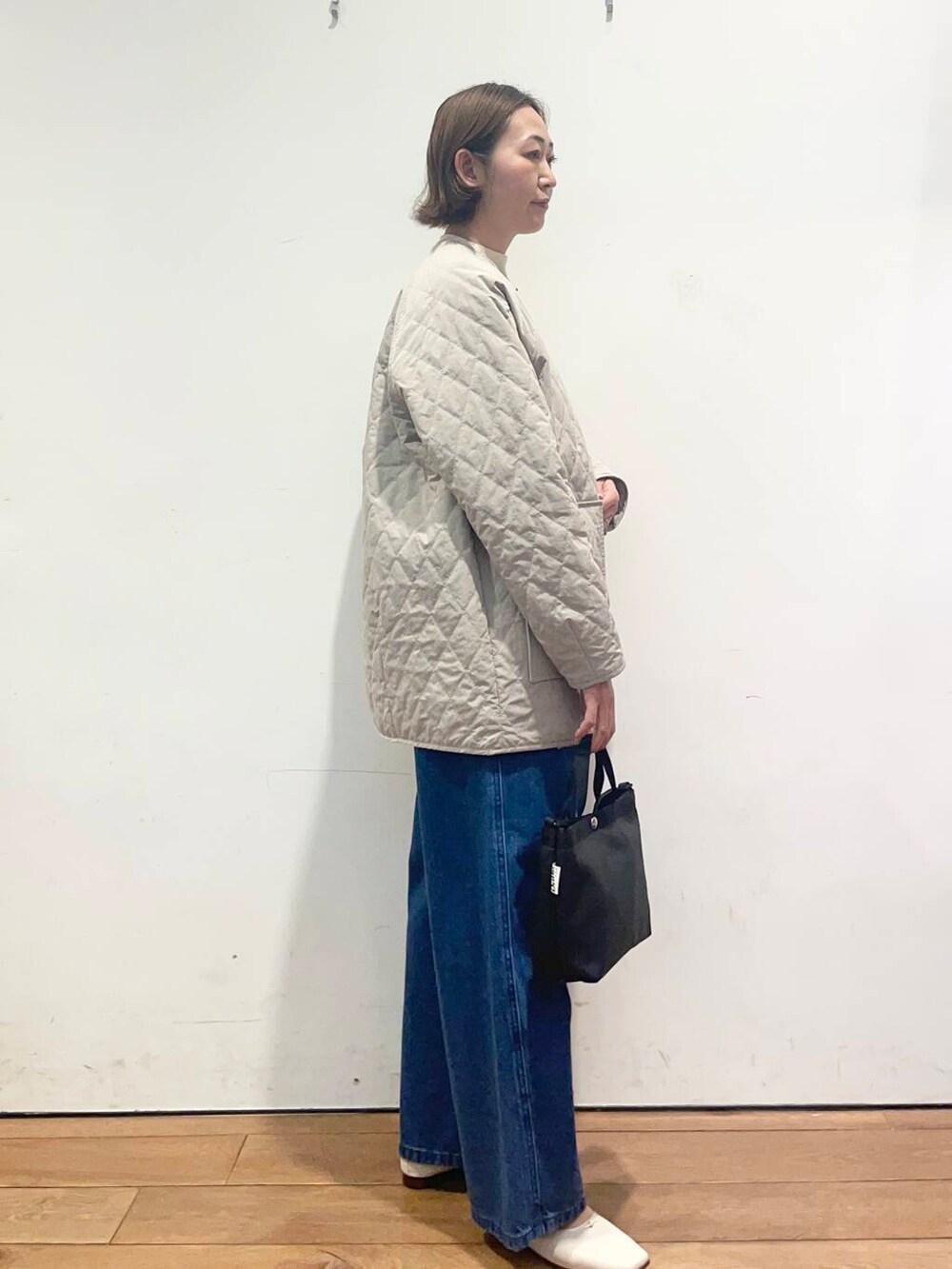 ブルー系のデニムパンツ、グレー系のダウンジャケット/コート、ブラック系のニット/セーターを着用したレディースの春コーディネートの4枚目の写真