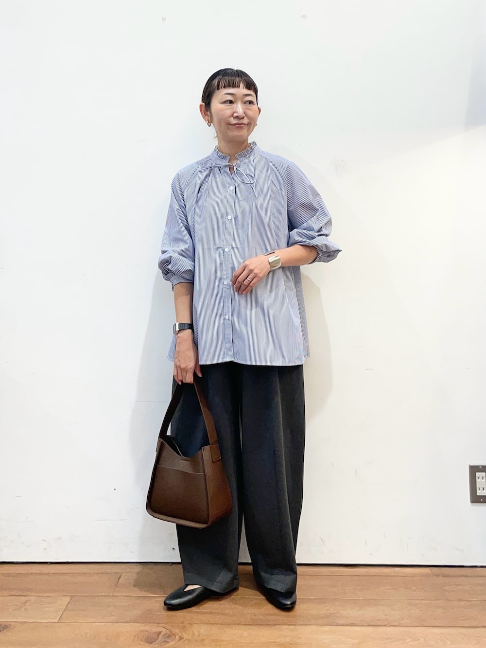 ブルー系のシャツ/ブラウス、グレー系のその他パンツ、ブラウン系のハンドバッグを着用したレディースの秋コーディネートの2枚目の写真