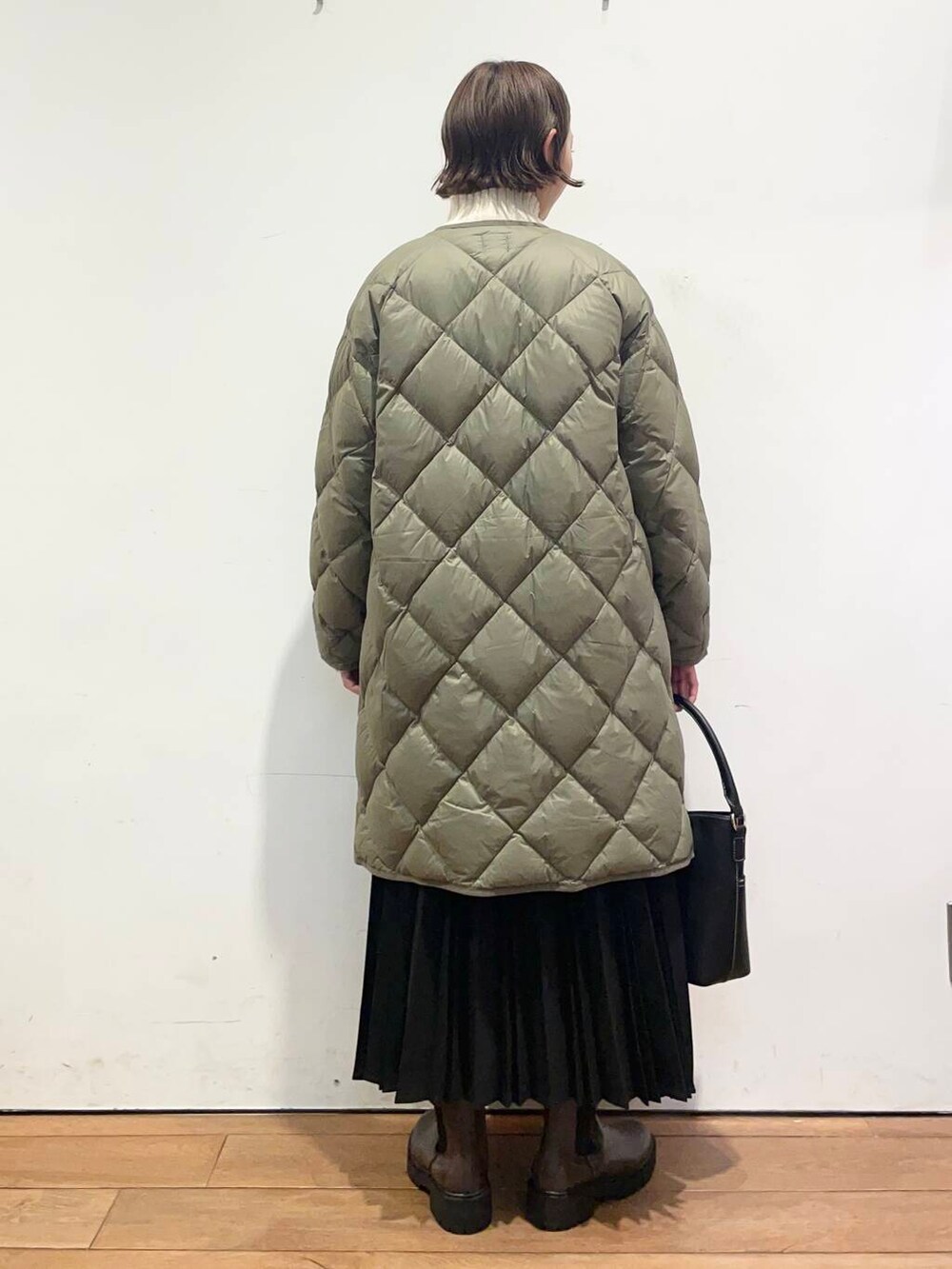 グリーン系のダウンジャケット/コート、ブラック系のハンドバッグ、ブラウン系のブーツを着用したレディースの冬コーディネートの4枚目の写真