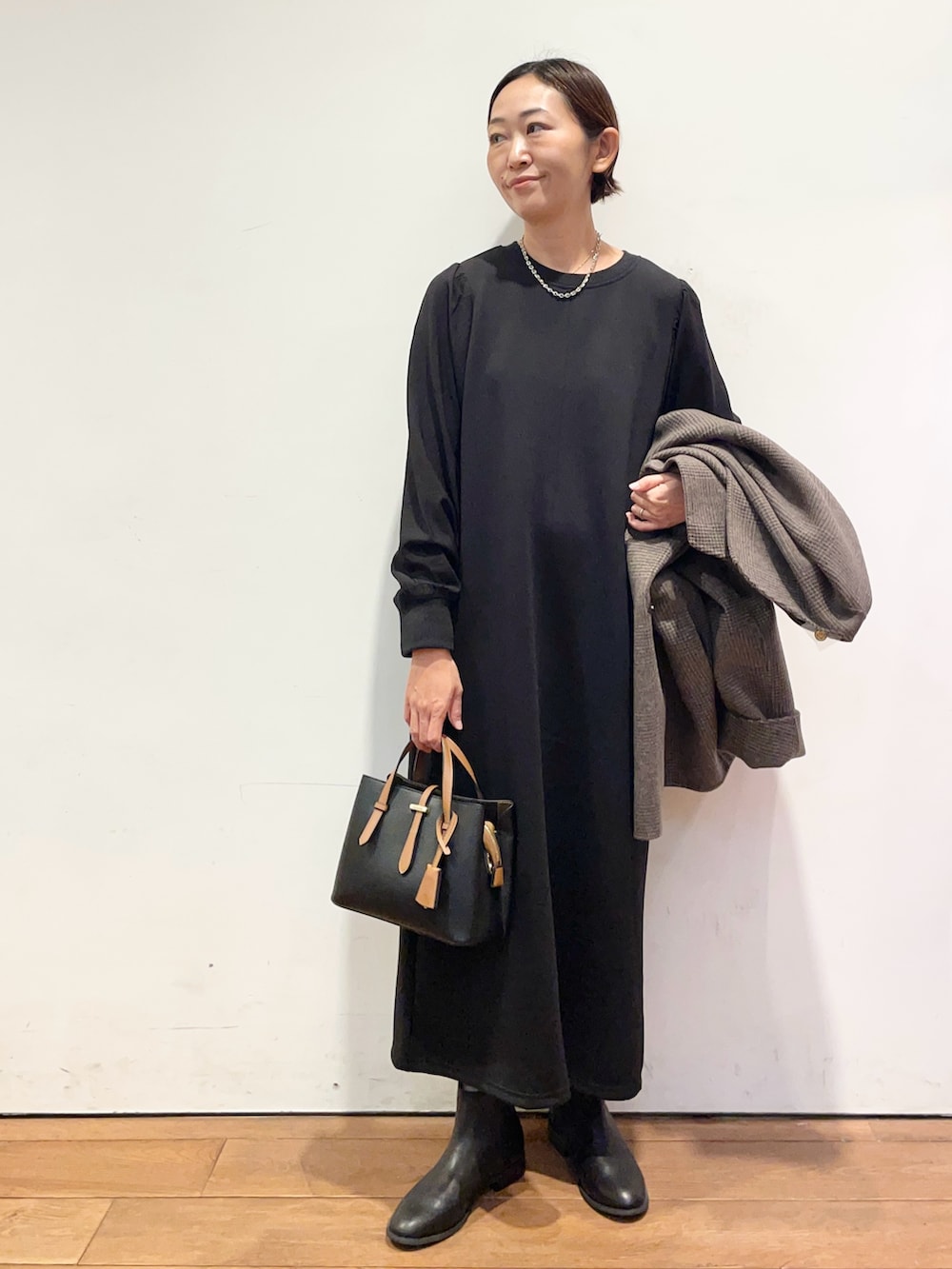 ブラック系のブーツ、ブラック系のハンドバッグ、その他のその他アウターを着用したレディースの秋コーディネートの5枚目の写真