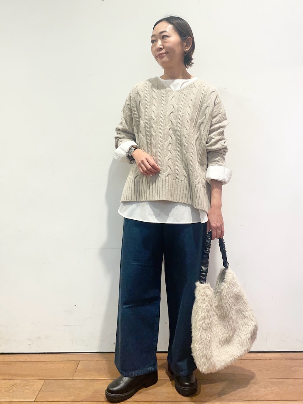 ベージュ系のニット/セーター、ホワイト系のシャツ/ブラウス、ブルー系のデニムパンツを着用したレディースの冬コーディネートの2枚目の写真