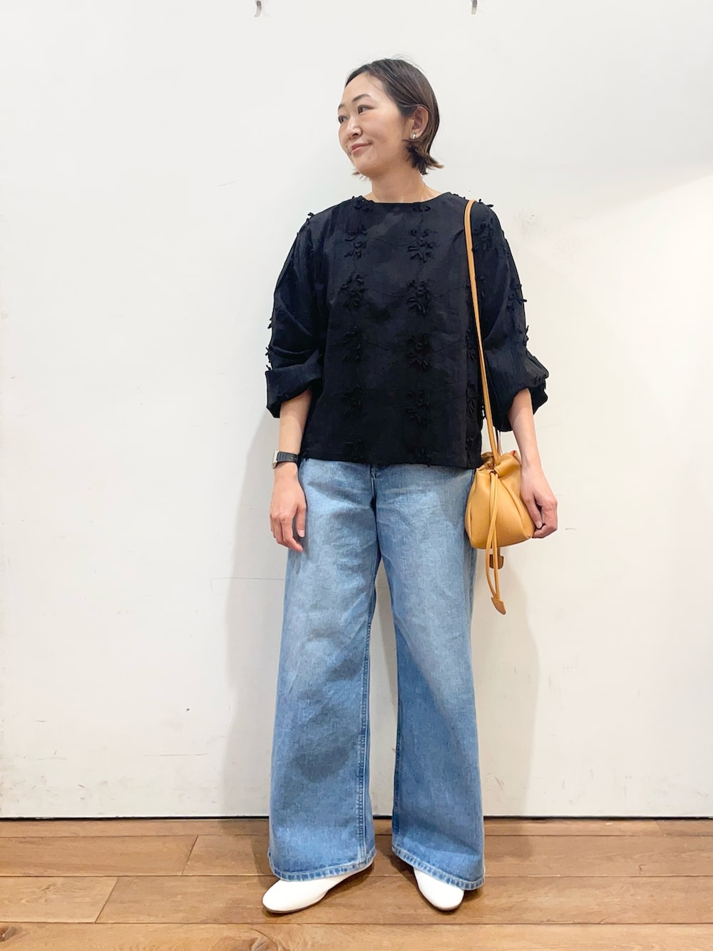 ブラック系のシャツ/ブラウス、ブルー系のデニムパンツ、オレンジ系のショルダーバッグを着用したレディースの冬コーディネートの2枚目の写真