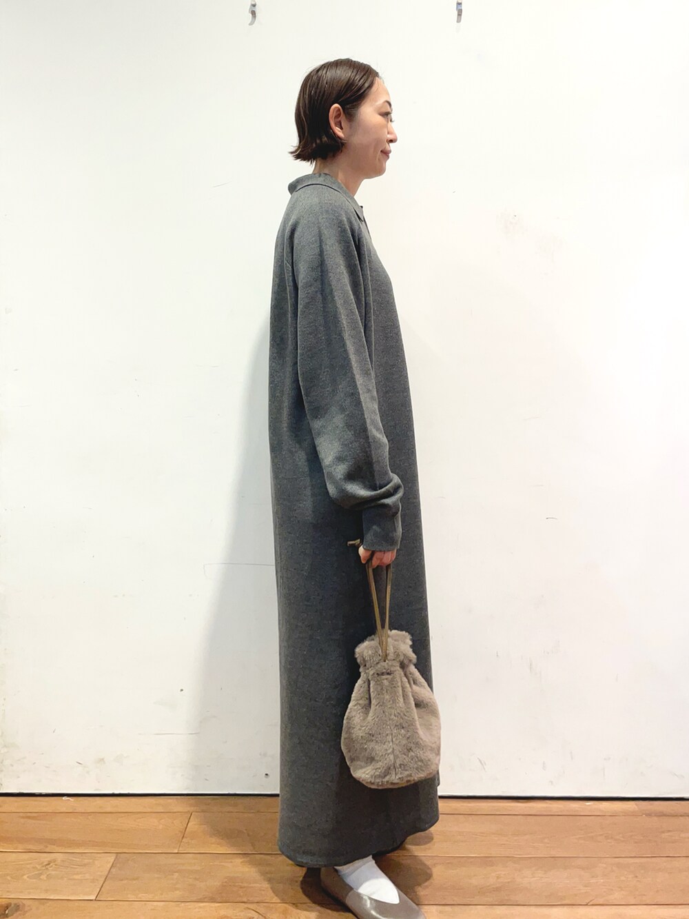 グレー系のワンピース、ブラウン系のショルダーバッグ、ベージュ系のパンプスを着用したレディースの秋コーディネートの3枚目の写真