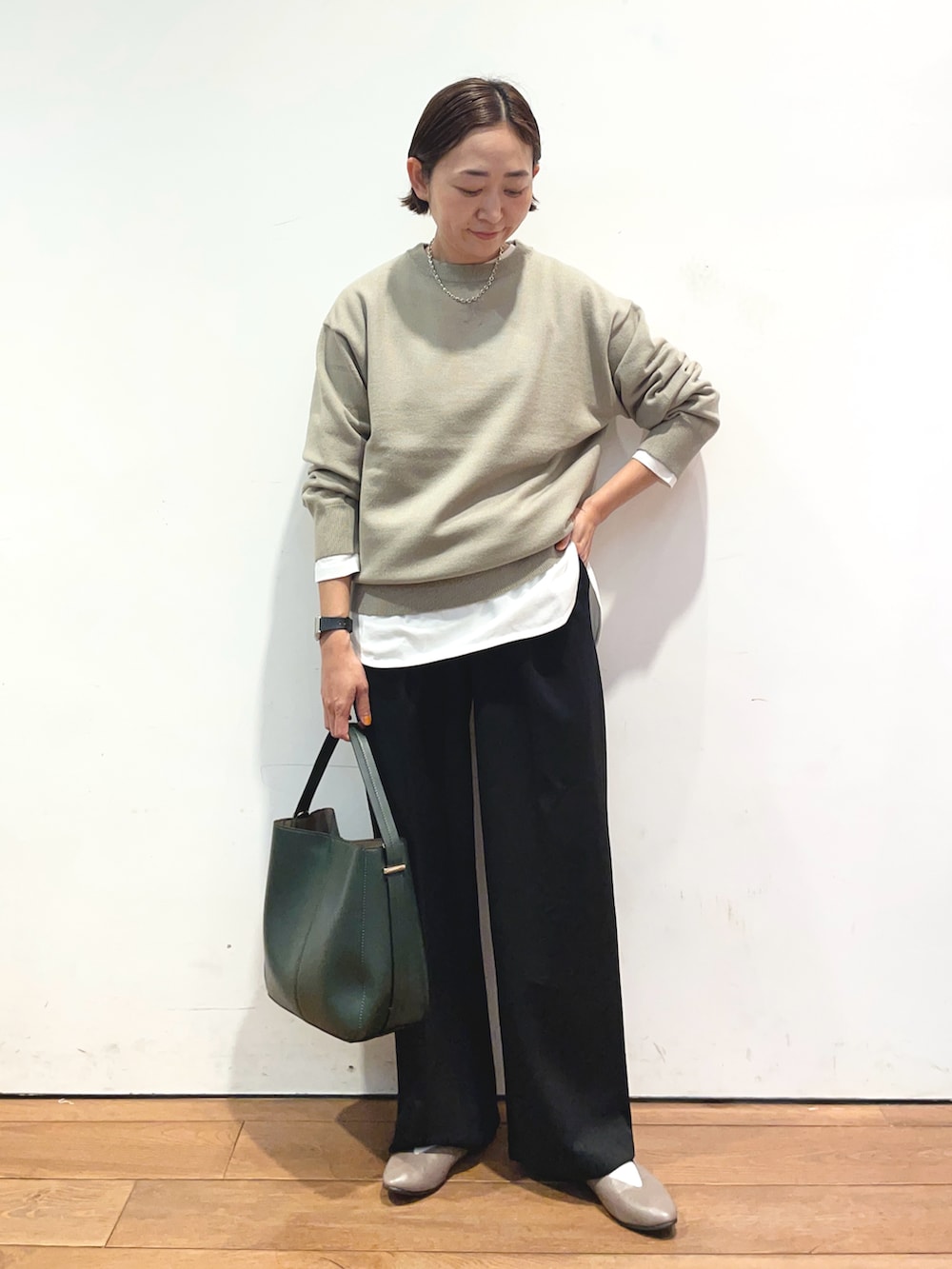 ベージュ系のニット/セーター、ホワイト系のTシャツ/カットソー、グリーン系のハンドバッグを着用したレディースの秋コーディネートの2枚目の写真