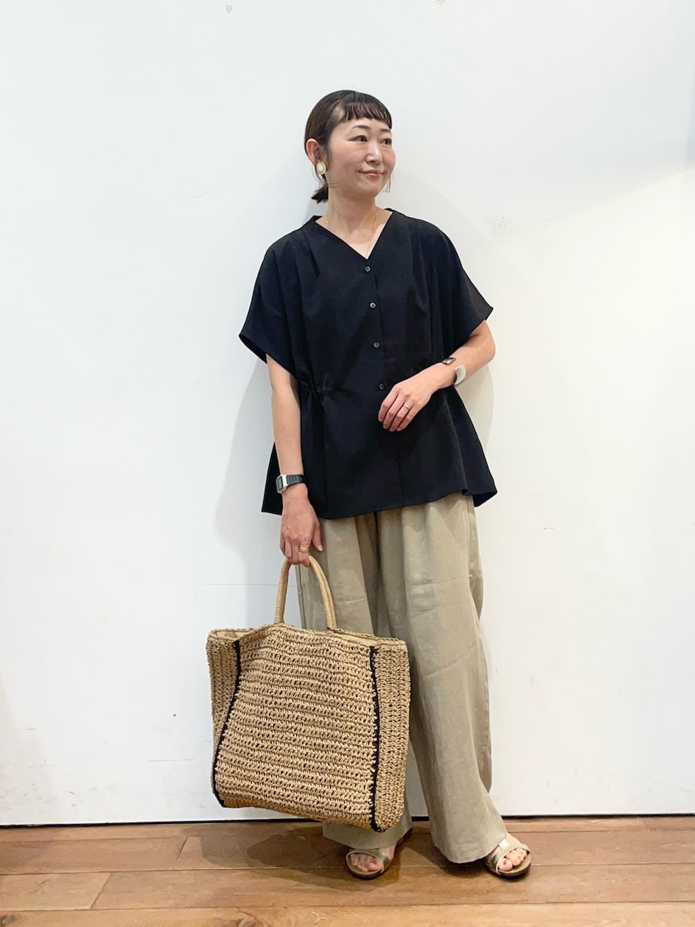 ブラック系のシャツ/ブラウス、ベージュ系のその他パンツ、ゴールド系のサンダルを着用したレディースの夏コーディネートの2枚目の写真