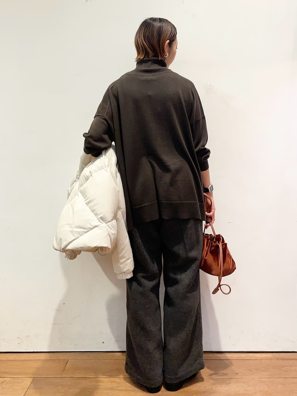 ホワイト系のダウンジャケット/コート、ブラウン系のニット/セーター、ブラック系のブーツを着用したレディースの秋コーディネートの8枚目の写真