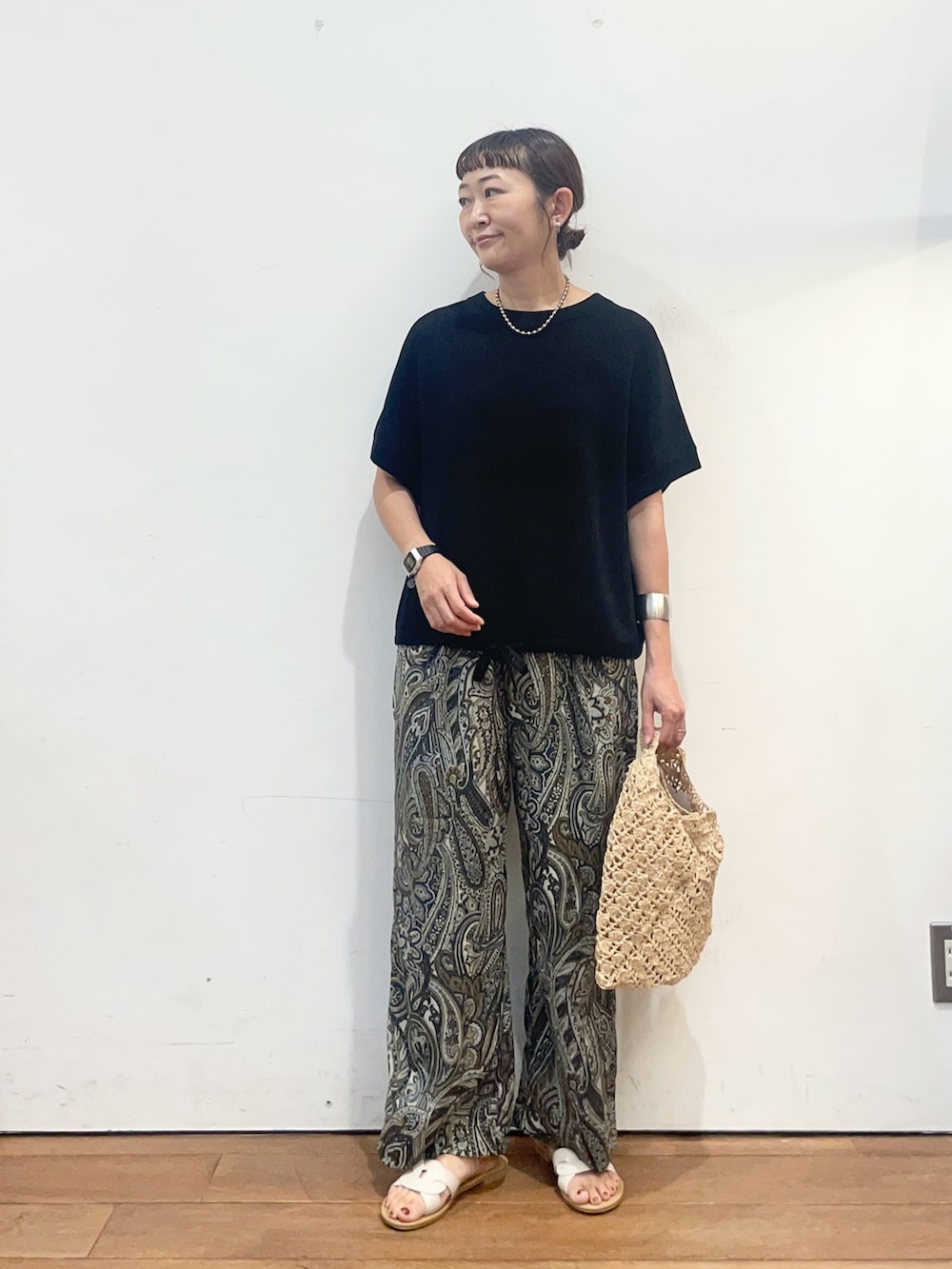ブラック系のニット/セーター、ベージュ系のハンドバッグ、ブラウン系のその他パンツを着用したレディースの夏コーディネートの2枚目の写真